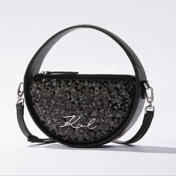 Black handbag with decorative pattern and visible brand name on a light gray background