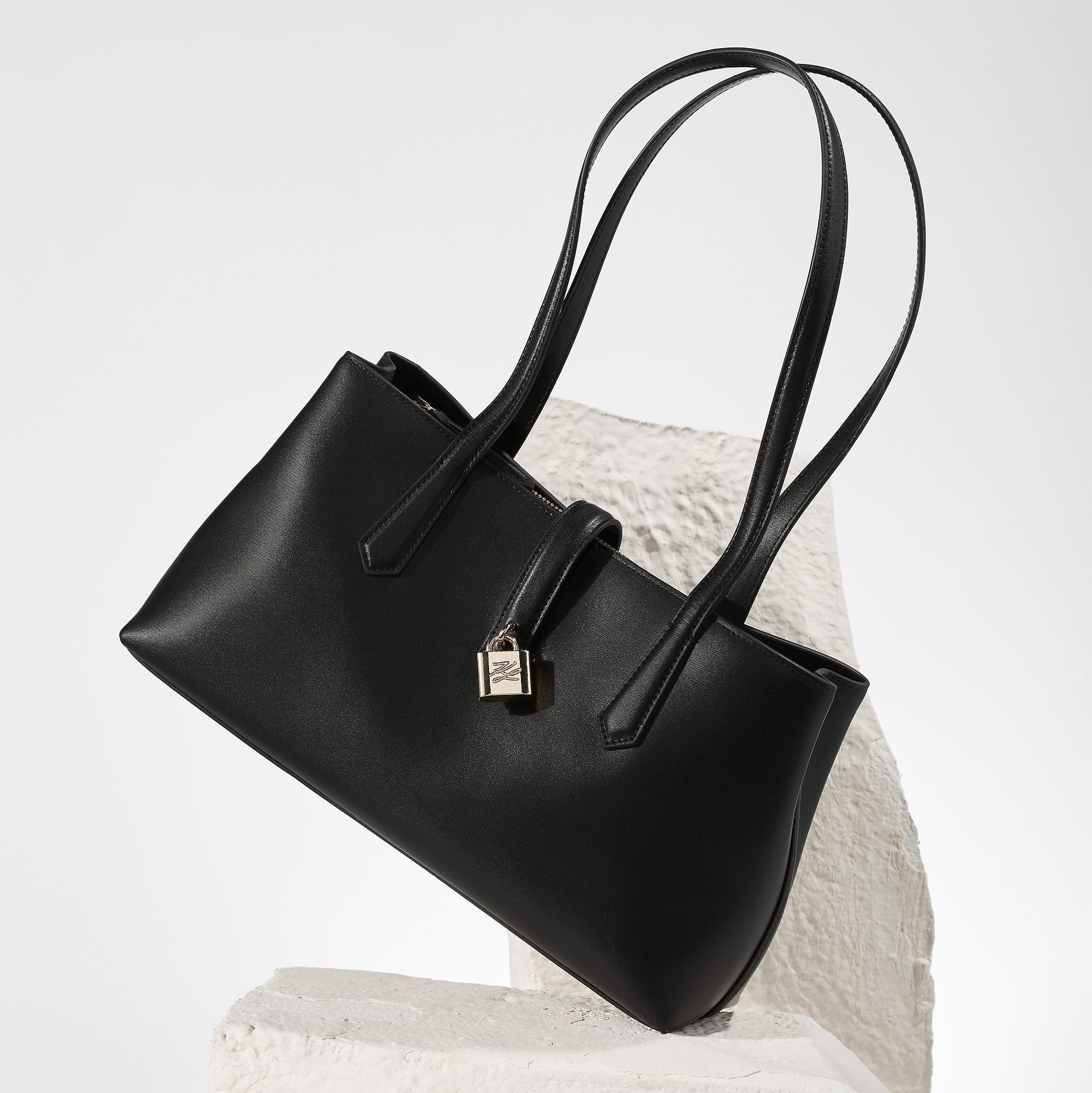 Black handbag on a textured white surface with a light gray background