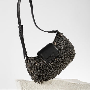 Black fringe handbag on a light gray background