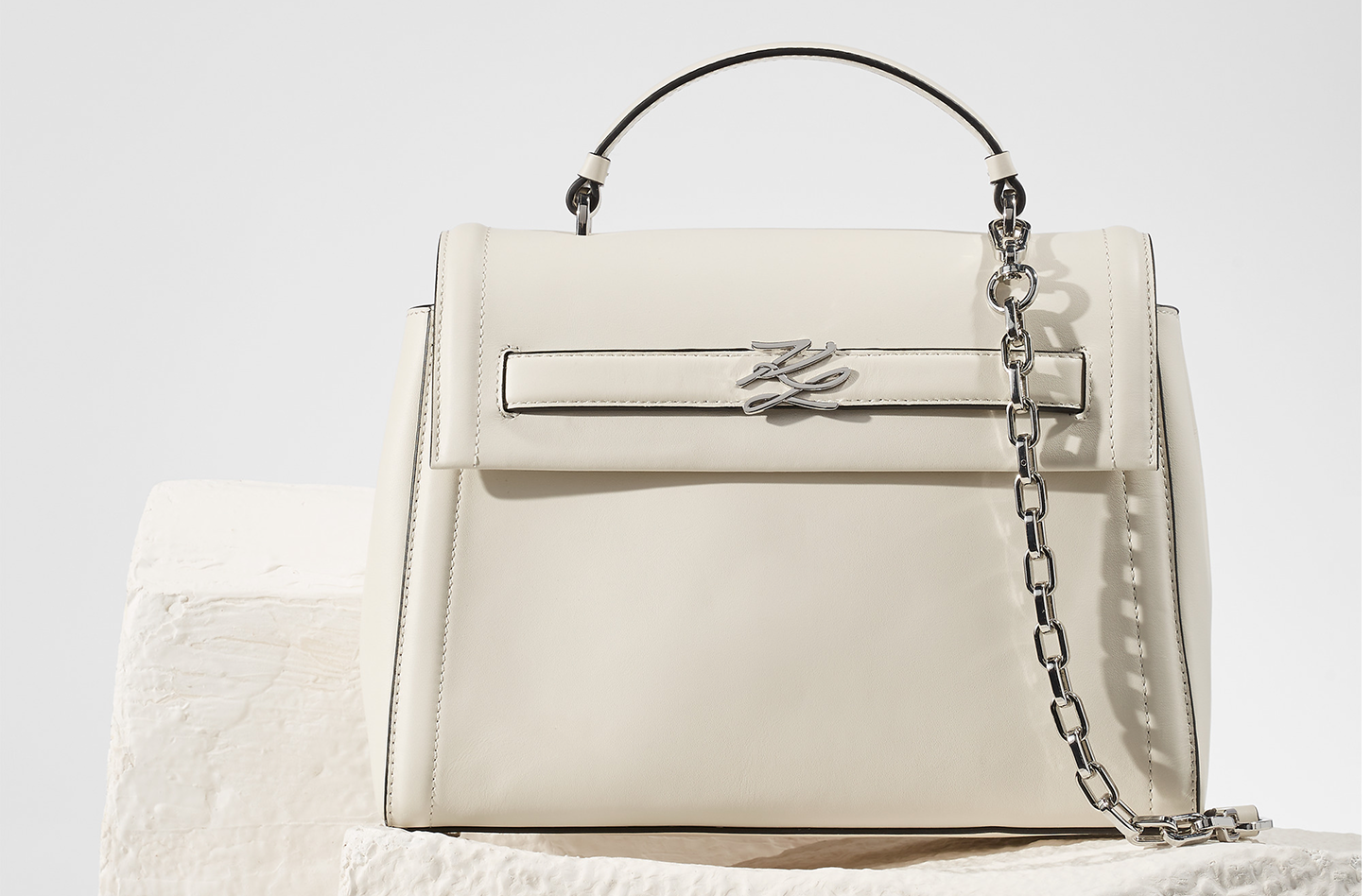 White handbag with a chain detail on a light gray background