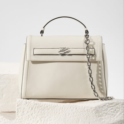White handbag with a chain detail on a textured white surface