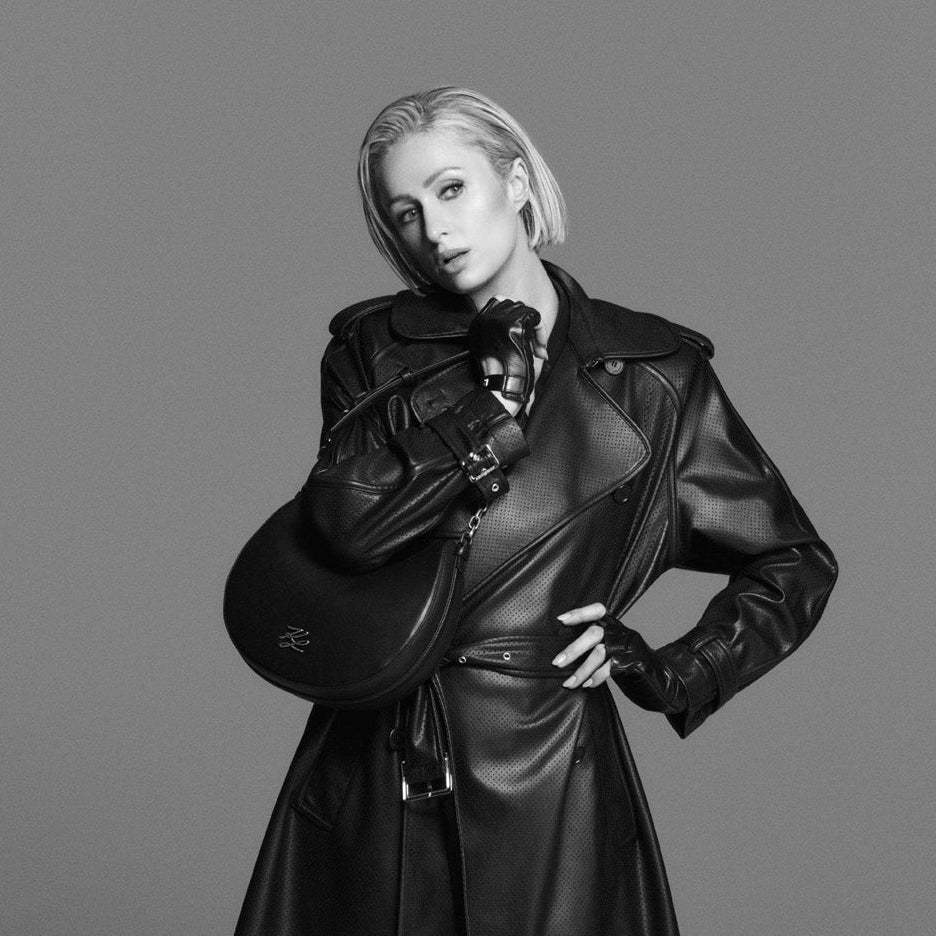 Person wearing a black leather trench coat on a gray background