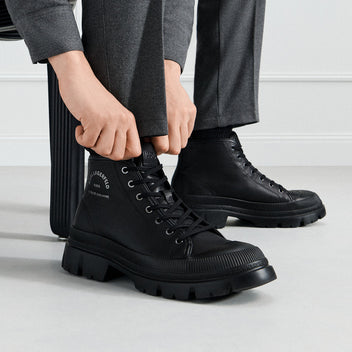 Person wearing black boots with a white background