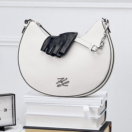 Handbag with a clock and books on a white surface