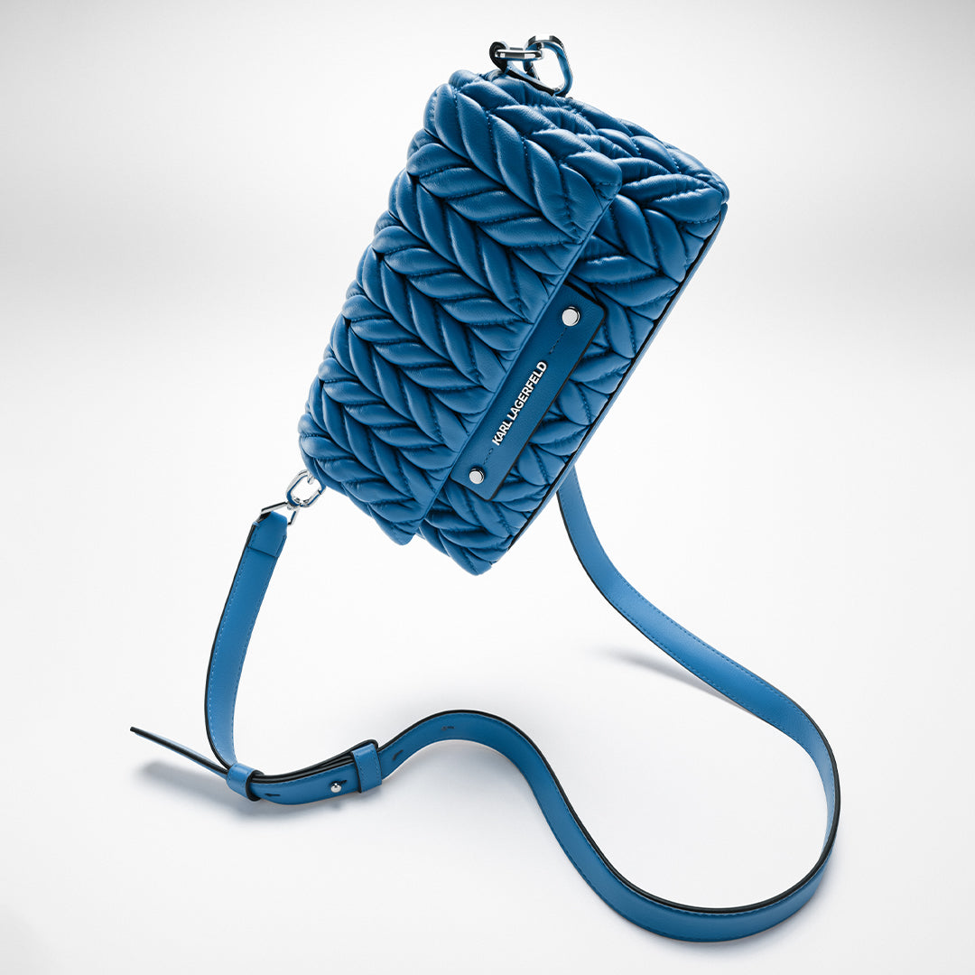 Blue quilted handbag with a strap on a white background