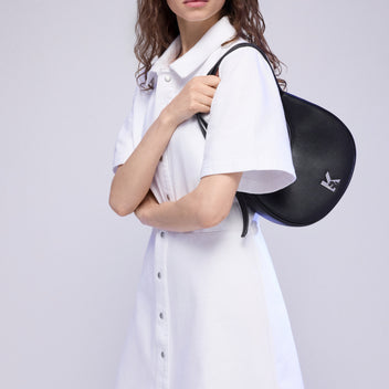 Woman wearing a white dress with a black backpack on a light gray background